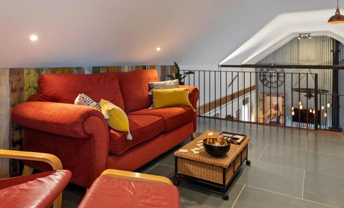 at the top of the stairs landing with large sofa and IKEA chair, smart TV, underfloor heating, clothes hanging rail, doors leading to bedroom and fami